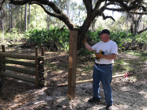 A volunteers levels a fence post at Lake Kissimmee State Park in Lake Wales,Fla. 